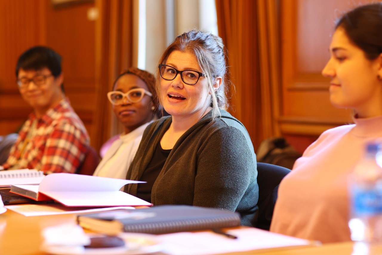 A diverse group of students sits at a table, reviewing papers and collaborating on their academic projects.