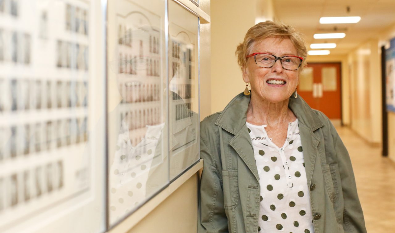 A woman leans against the wall in a hallway