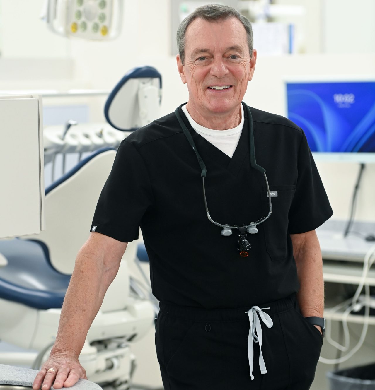 Boran in black scrubs standing smiling in a dentistry clinic.