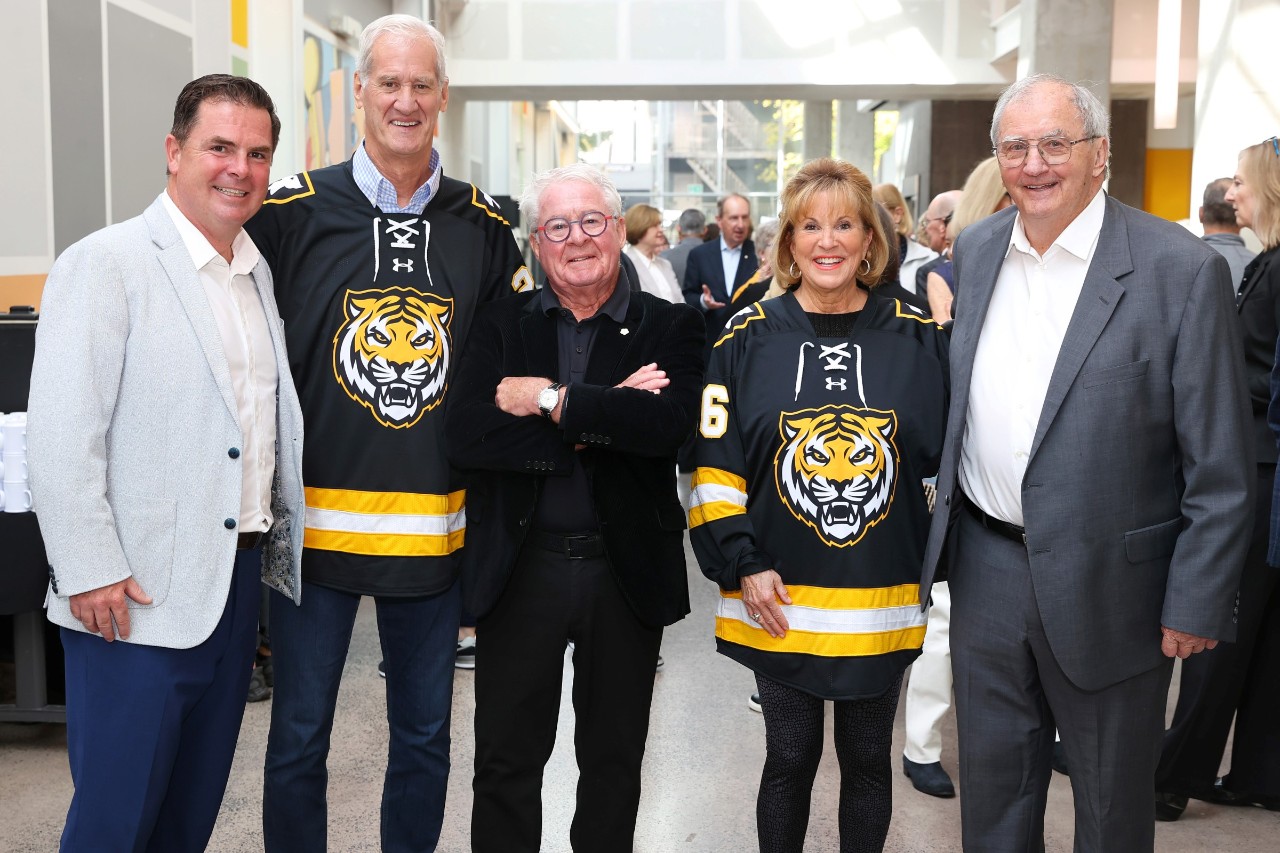 Four men and a woman stand together at a gift announcement event.