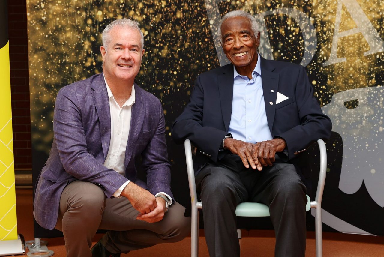 Dawe and Oliver, seated in chair, together at an event. 