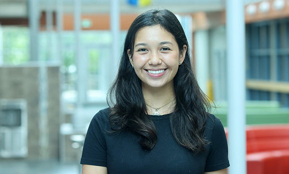 A woman wearing a black t-shirt smiles at the camera