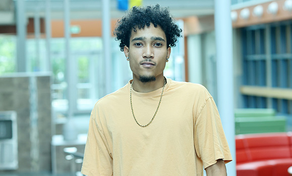 A man wearing a yellow t-shirt standing in an atrium