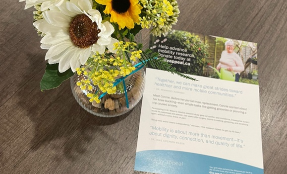 A vase of flowers, yellow and white, atop a table with a brochure.