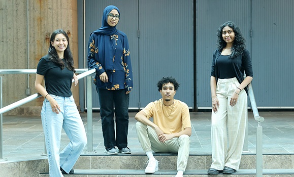 A group of four people stand on a stairwell with one person seated