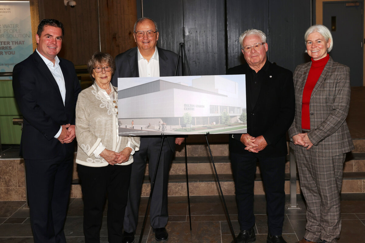 A group of people wearing suits standing around a board displaying a rendering image of a building