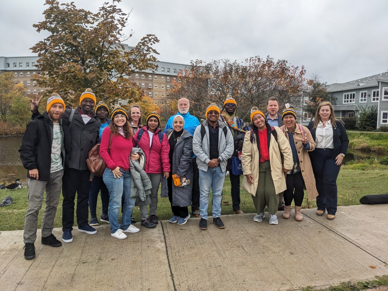 A diverse group of students and members of the institutes standing outside in toques in fall weather.
