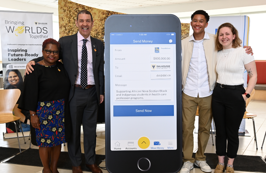Four people pose around a display board shaped like an iphone.