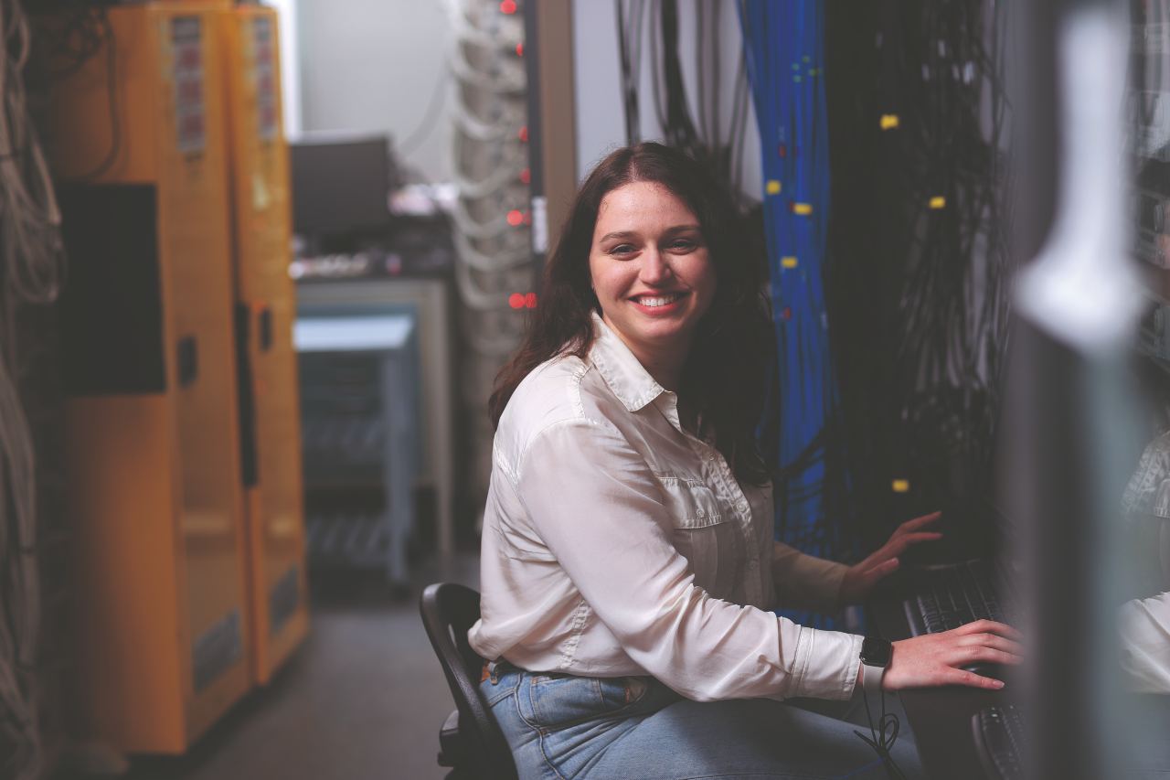 A woman with brown hair sits at a computer