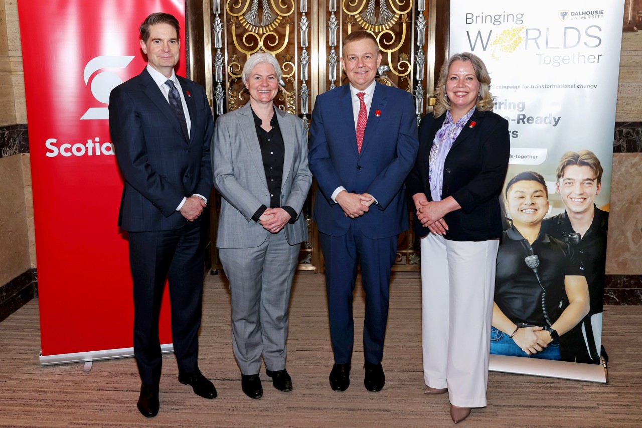 Dalhousie president and vice-chancellor Dr. Kim Brooks stands alongside Scotiabank representatives in front of banners for the bank and the Bringing Worlds Together campaign