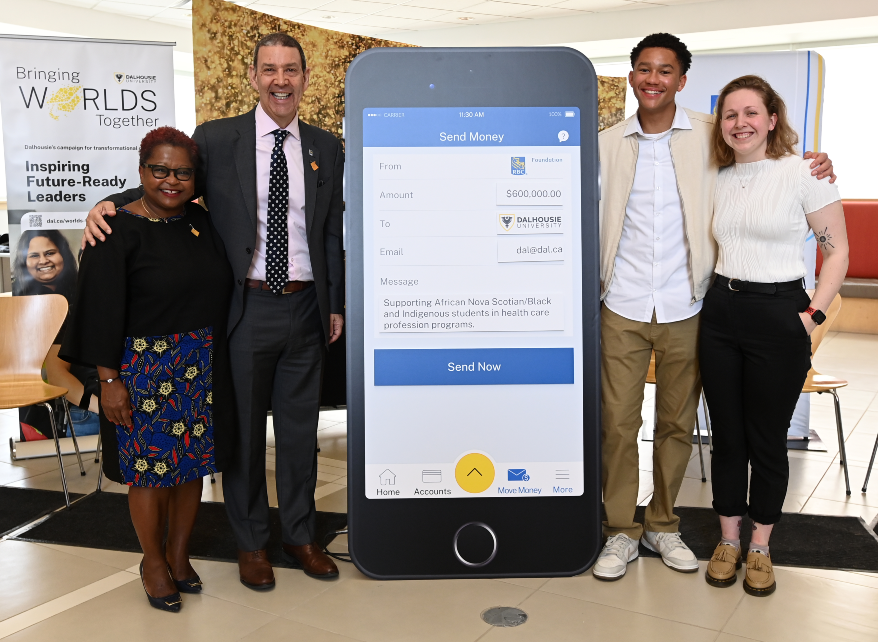 Four people pose around a display board shaped like an iphone.