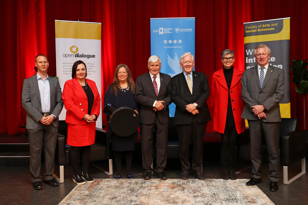 A group of seven people standing in front of three banners