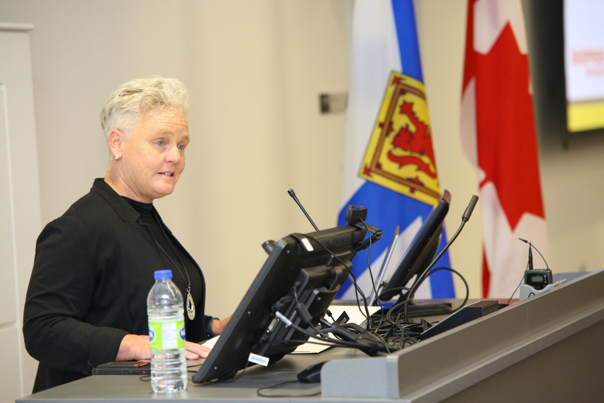 A woman wearing a black jacket standing at a podium