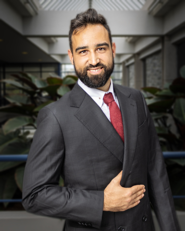 A man wearing a dark grey suit and red tie