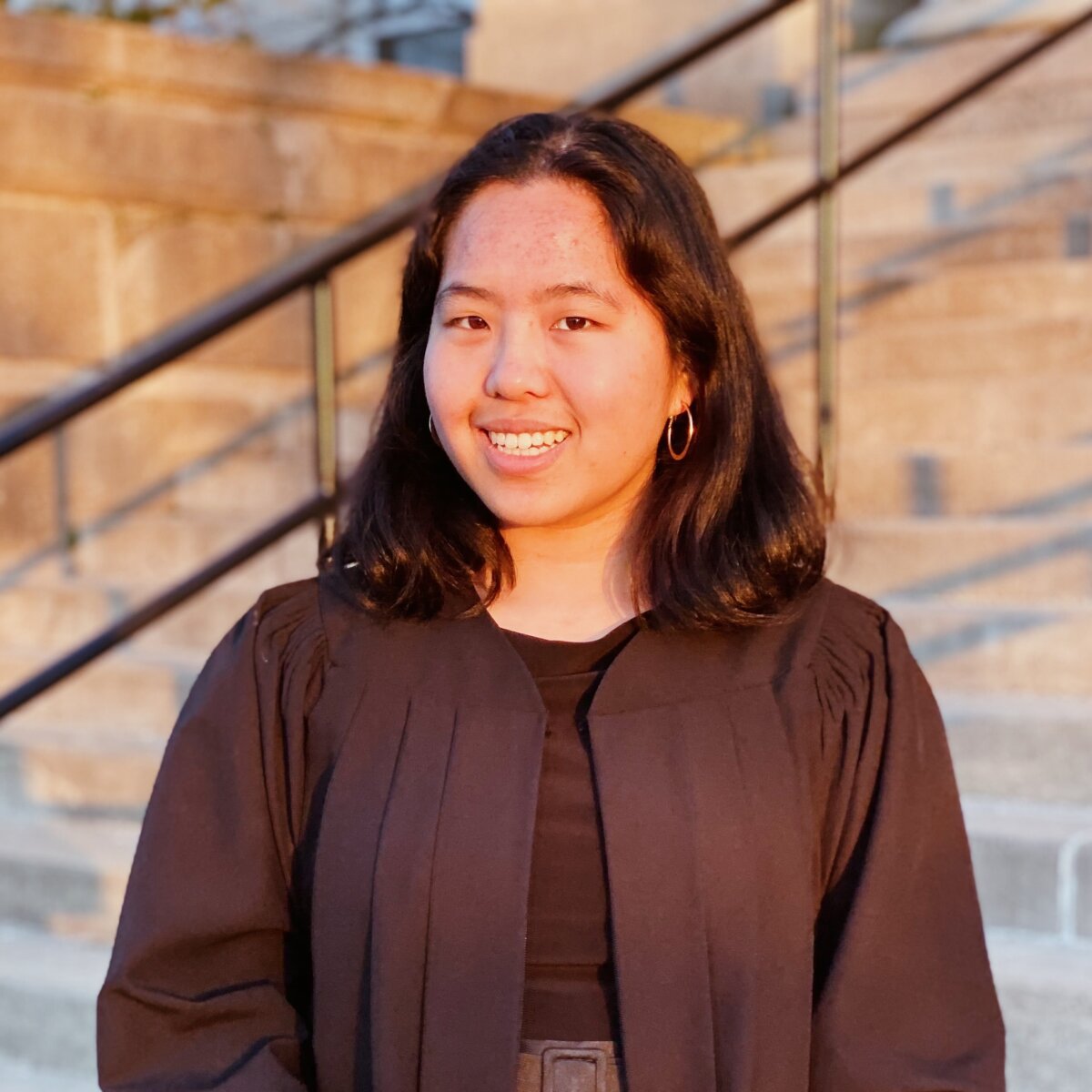A woman wearing a black jury robe standing in front of stone steps