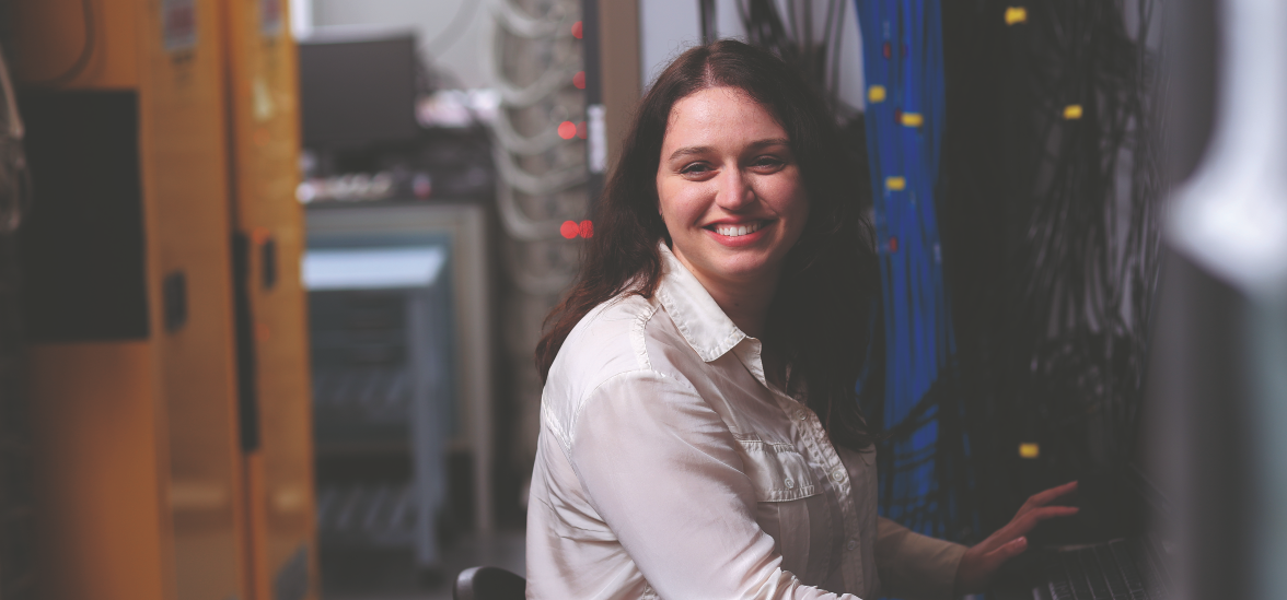 A woman with brown hair sits at a computer