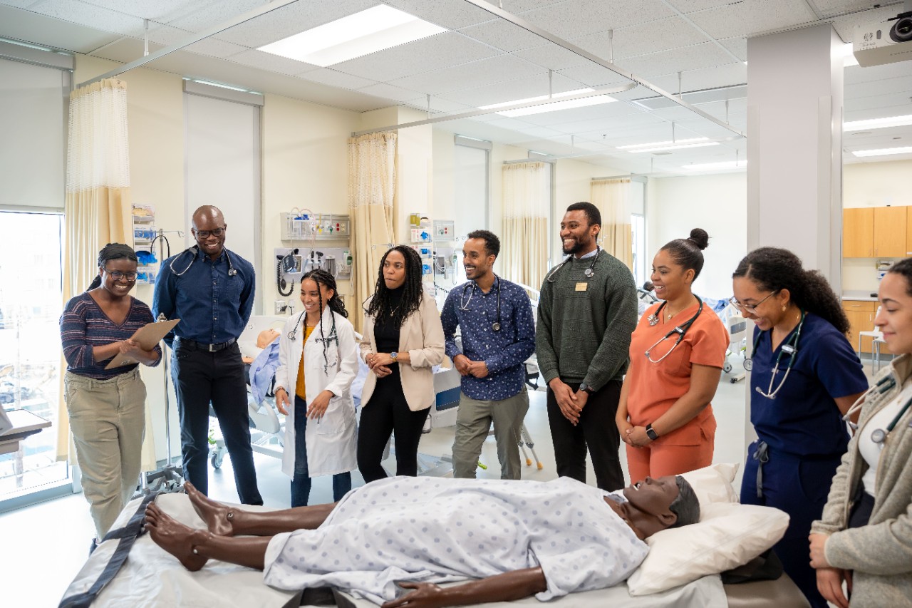 Group of health students gather around a mannikin in the simulation lab.