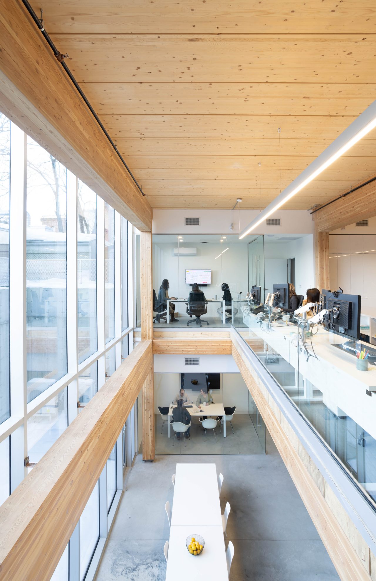 View from the second story of an open concept office space with wood ceilings and beams while people are at work.