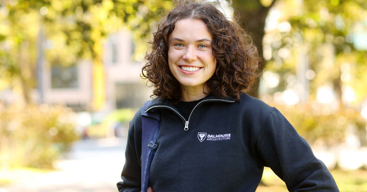 A woman wearing a Dalhousie sweater poses outside