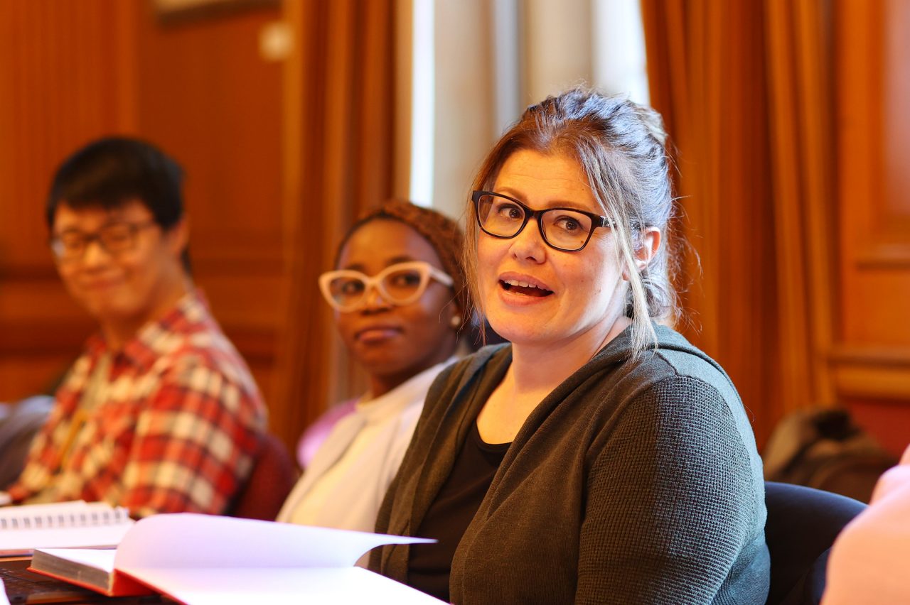 A diverse group of students sits at a table, reviewing papers and collaborating on their academic projects.