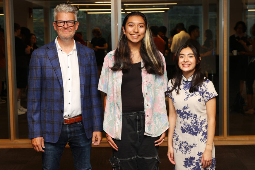 A man and two students stand together facing the camera