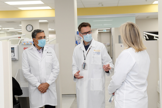 Three dentists wearing lab coats and surgical masks in a clinic.
