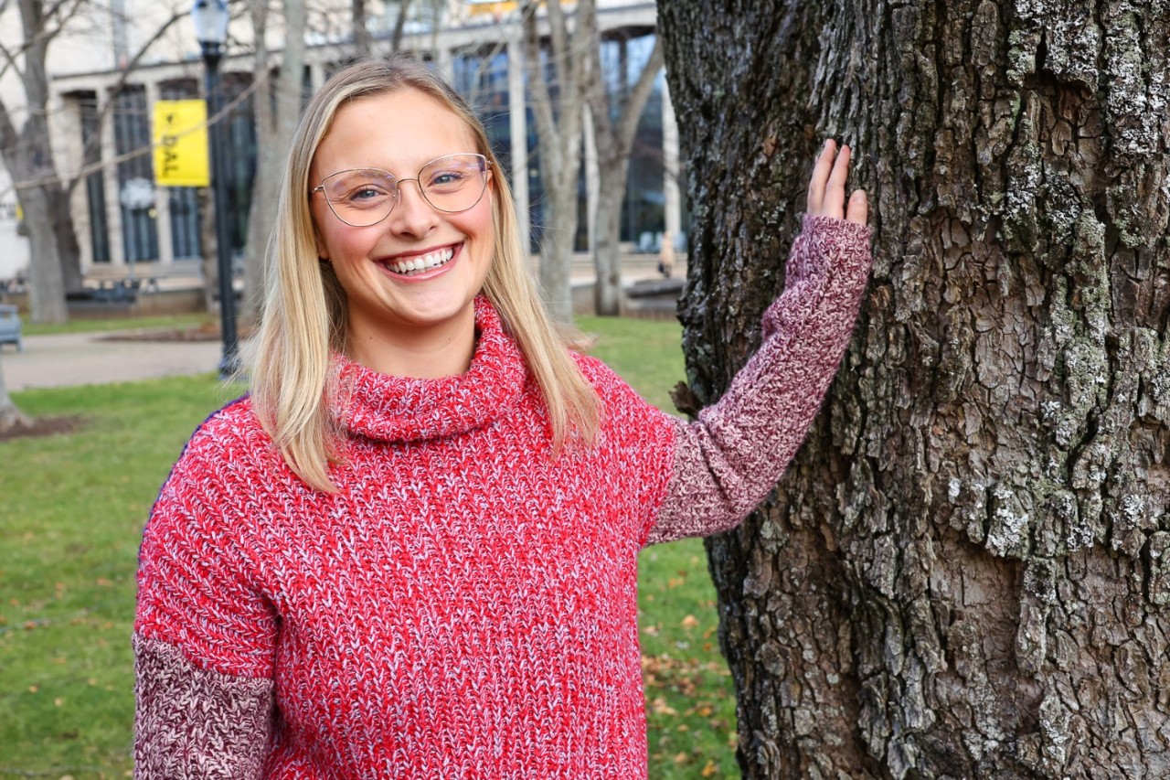 Allison True portrait outdoors leaning on tree.