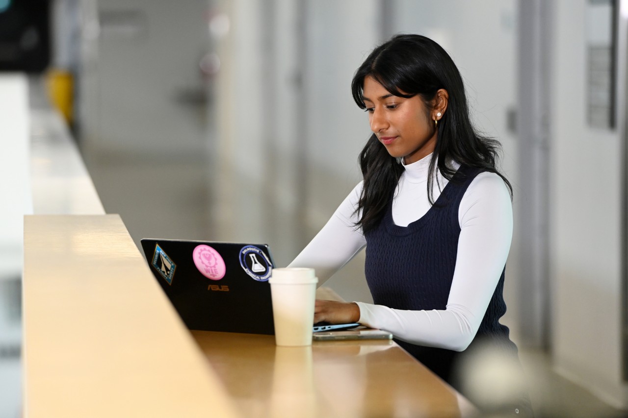 Natarajan seated working on a laptop with a coffee.