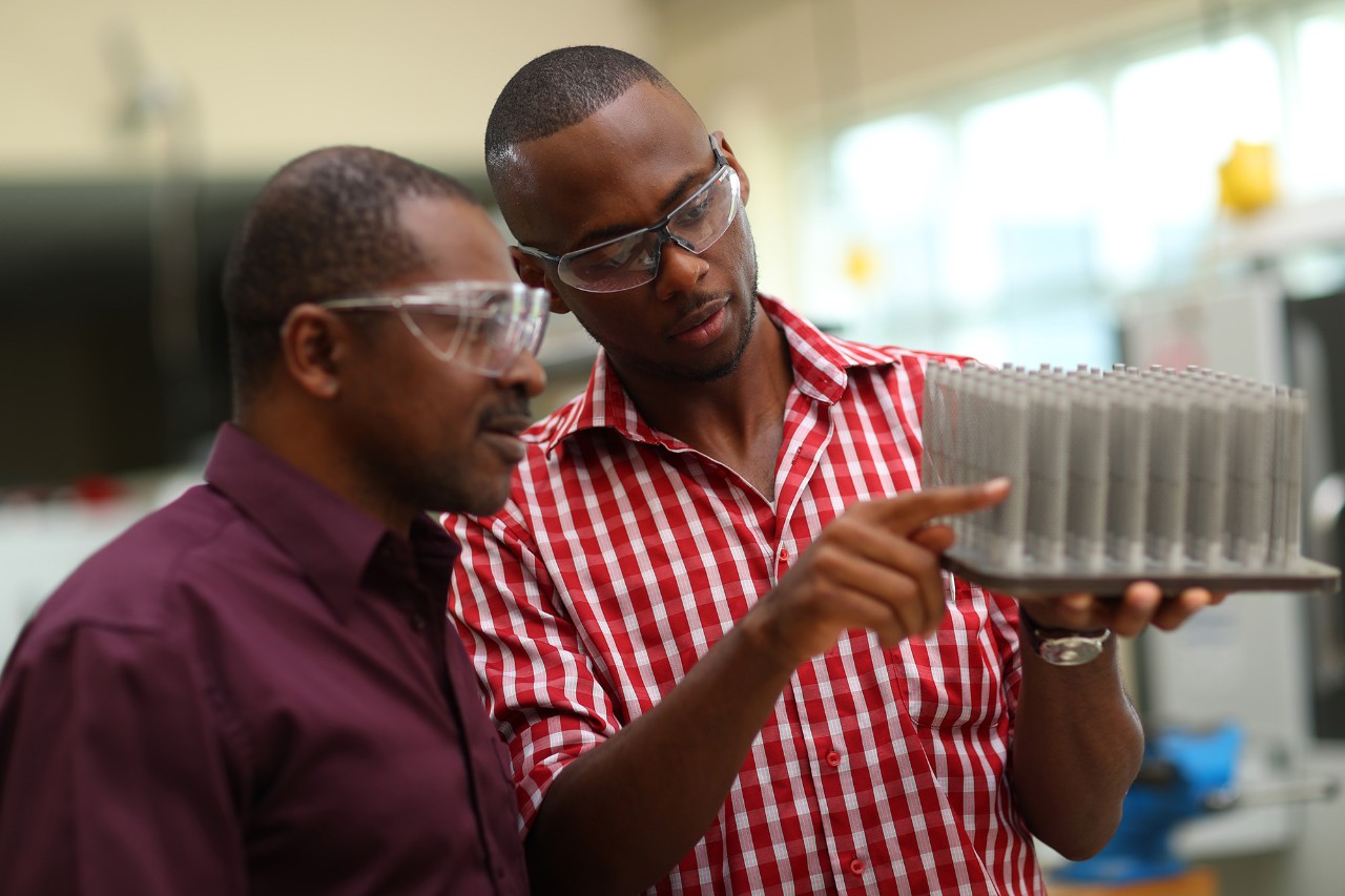 Student participating in co-op work examining an object with their mentor