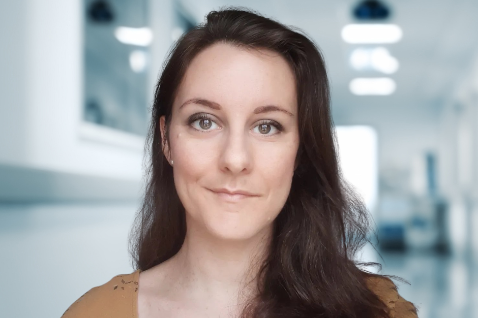 A woman with brown hair with a hospital hallway in the background