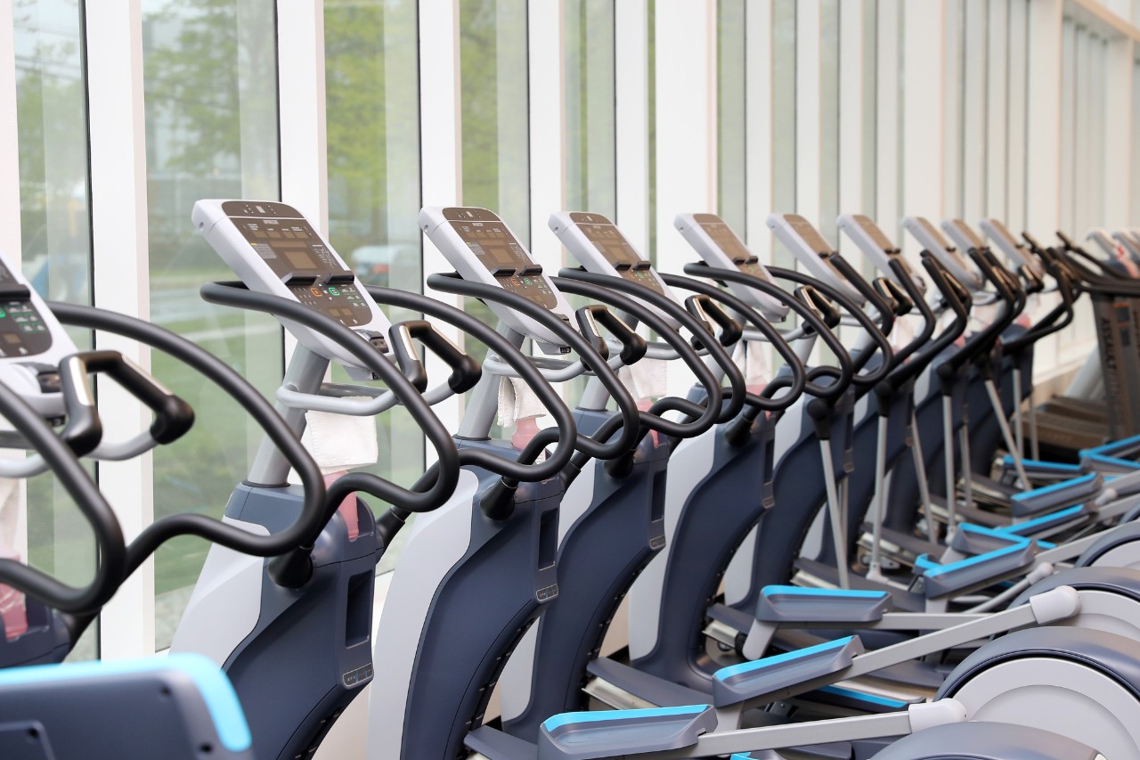 A row of exercise bikes in front of floor-to-ceiling windows.