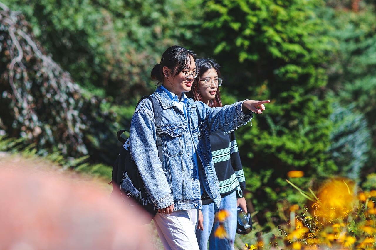 2 students outdoors walking on campus.