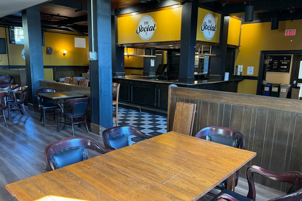 The Social pub, with wooden tables and chairs, yellow walls and a logo above the bar