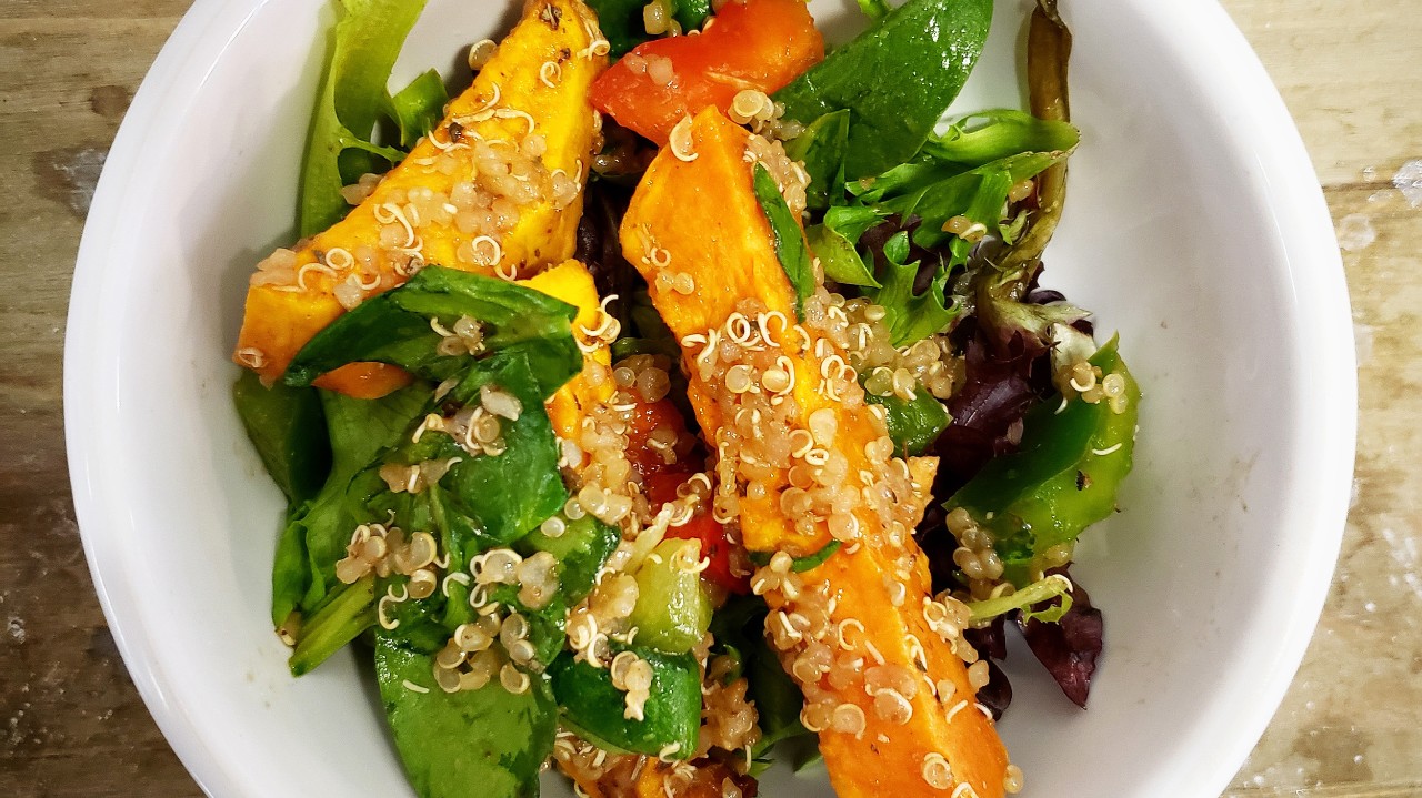 A bowl of colourful vegetables and quinoa with wedges of sweet potatotes