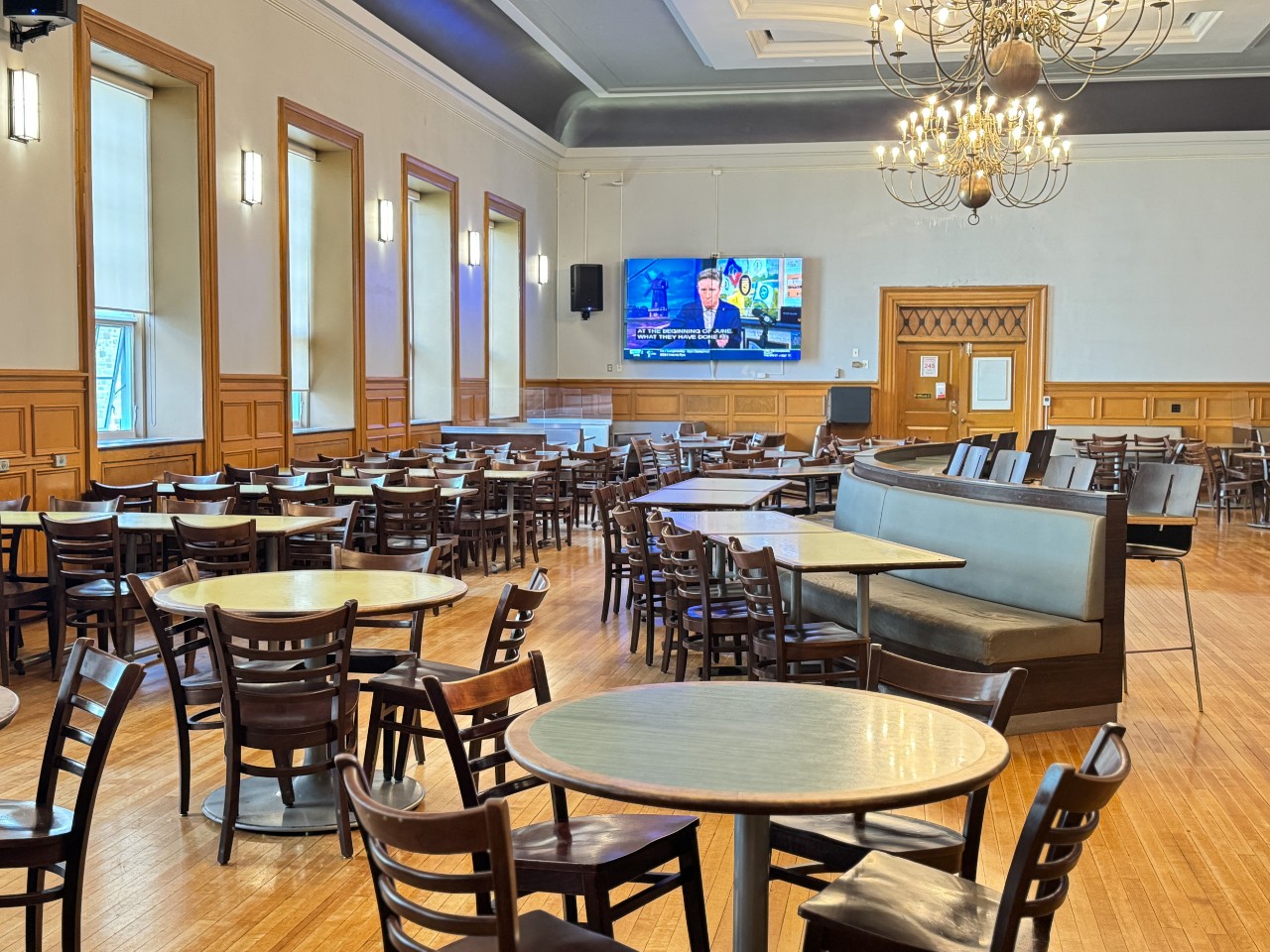 The seating area has plenty of different types of tables and seating and a large TV on the wall near the entrance