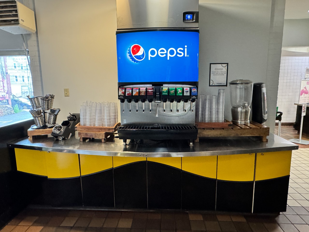 The drink station features sodas, water, juice, and cups.