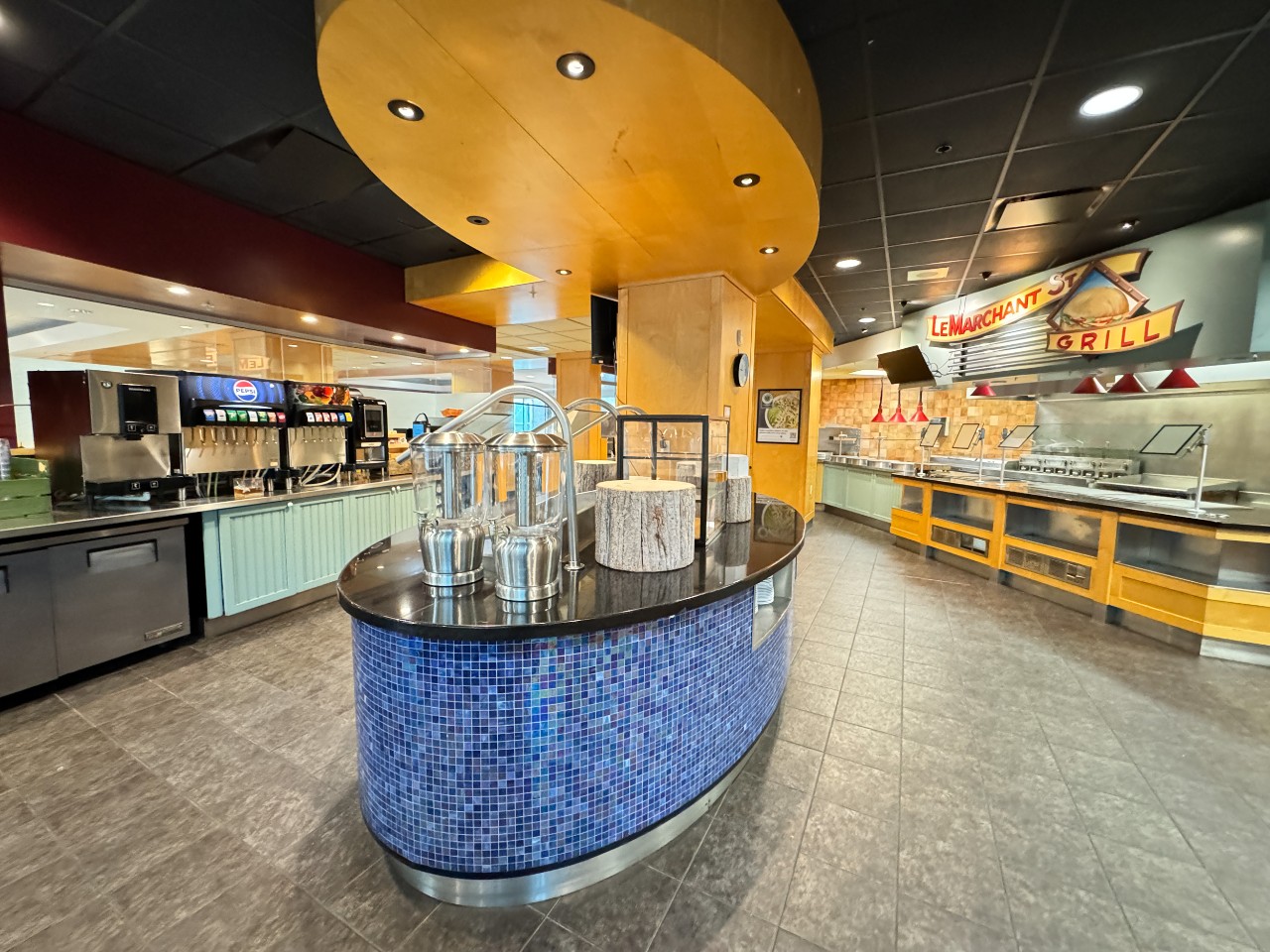 The centre island in the Risley dining servery is covered with colourful blue tiles and has bright lights above