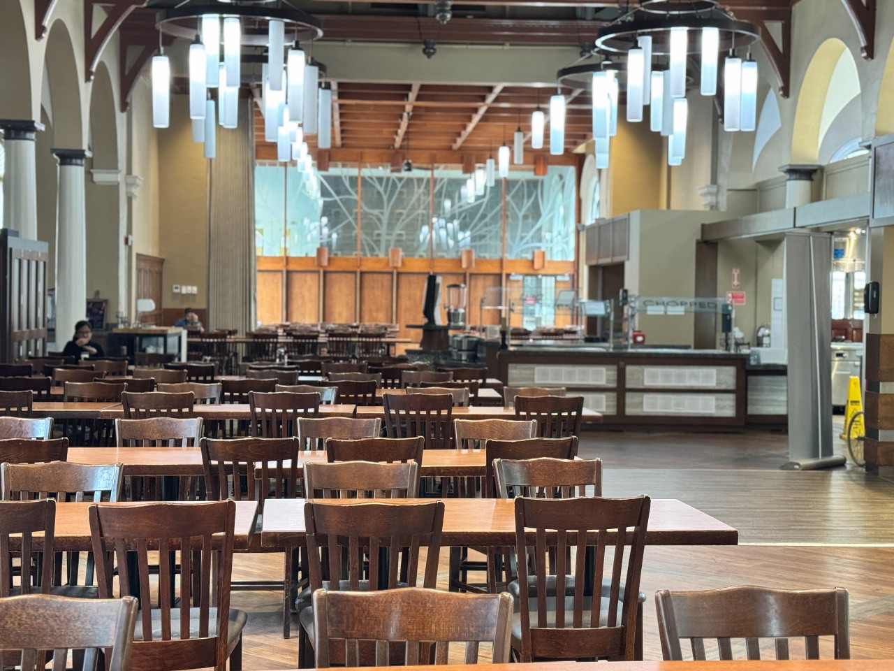 The seating in Shirreff dining hall is made of long tables with dark wooden chairs. Above are large chandeliers with lots of light.