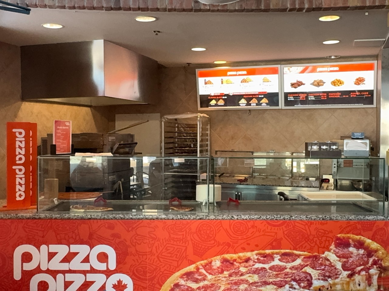 The counter at the PizzaPizza location in the LSC - with pizza ovens and racks and a glass cover