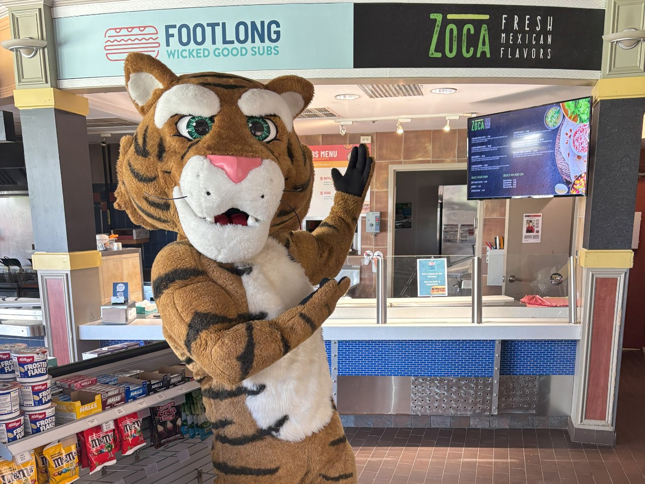 The Dal Tiger gestures toward the signs at Zoca and Footlong in the LSC