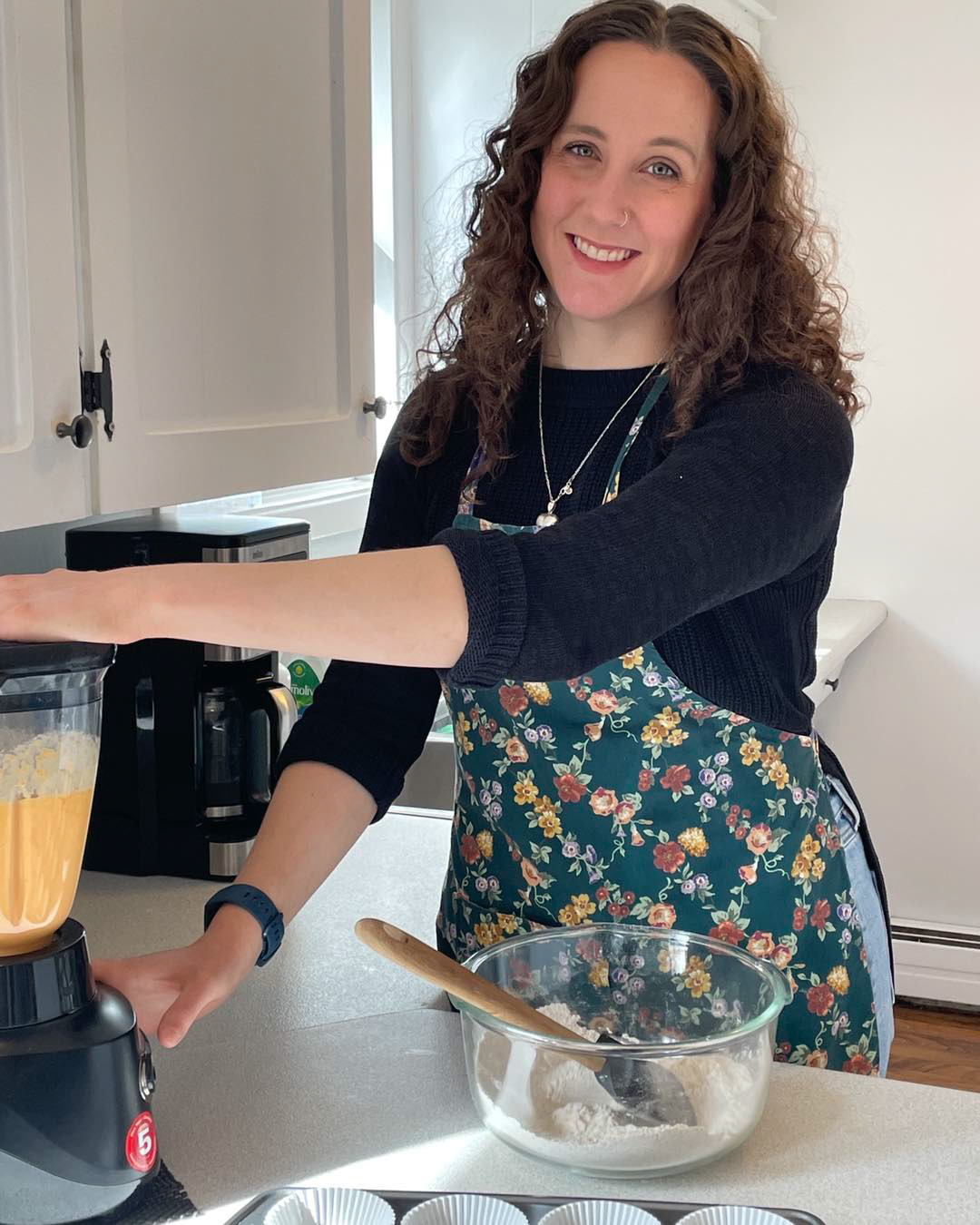 A photo of Liz Muggah, a woman with curly brown hair, in a kitchen