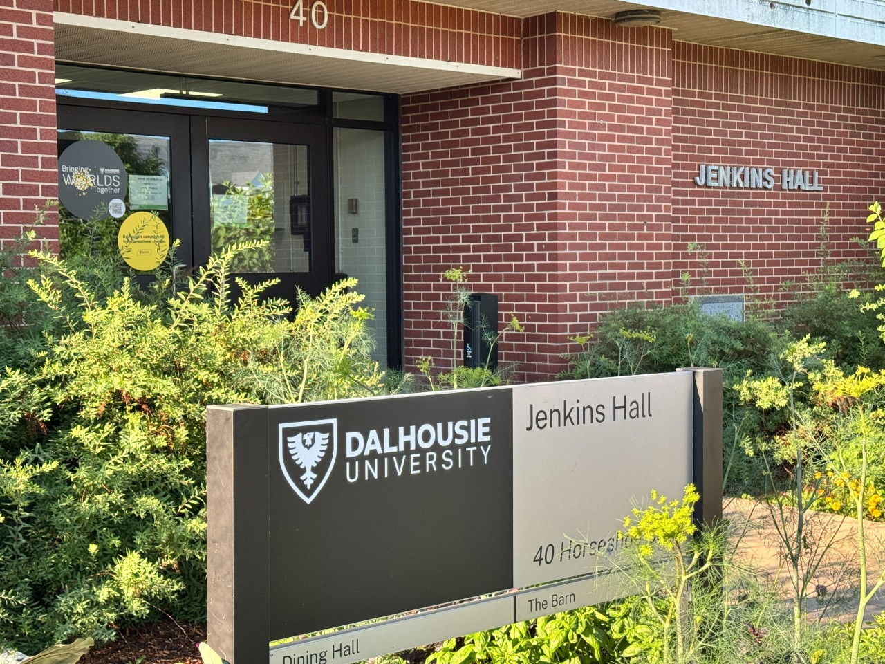The sign for Jenkins Hall sits in green bushes by the front door