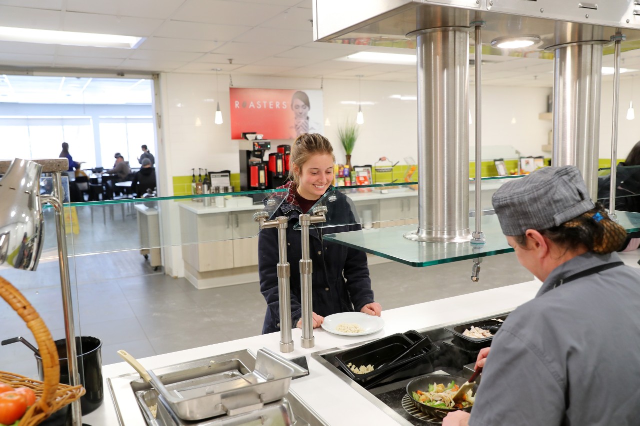 A staff member serves a made to order stir fry to a student