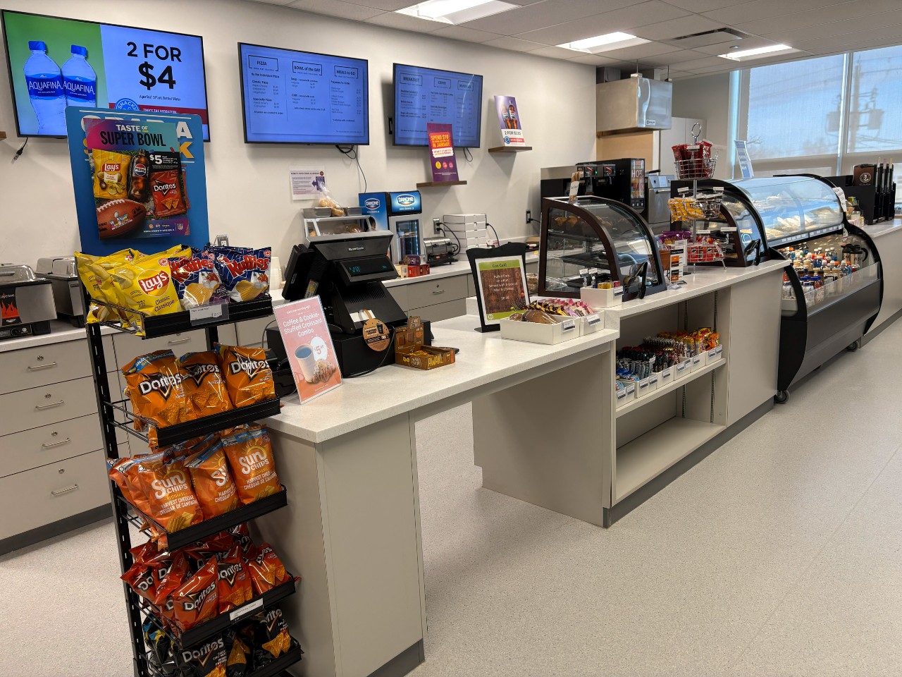 A wide photo of the Cox Café counter shows a rack of chips and several display cases of ready-to-eat options.