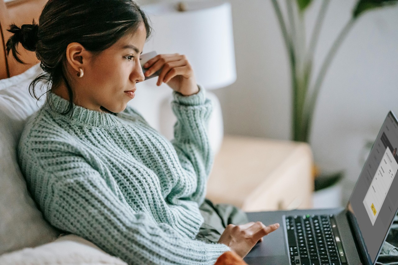 A young woman looks at her DalCard account page on a laptop, holding a credit card in the other hand