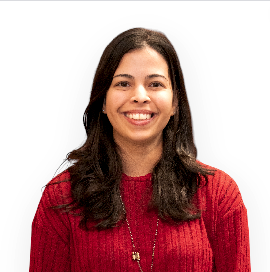 A portrait of Patricia smiling and wearing a red sweater and necklace.