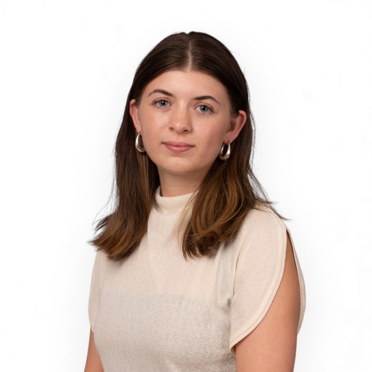 A portrait of Amelie dressed in a white top and earrings.