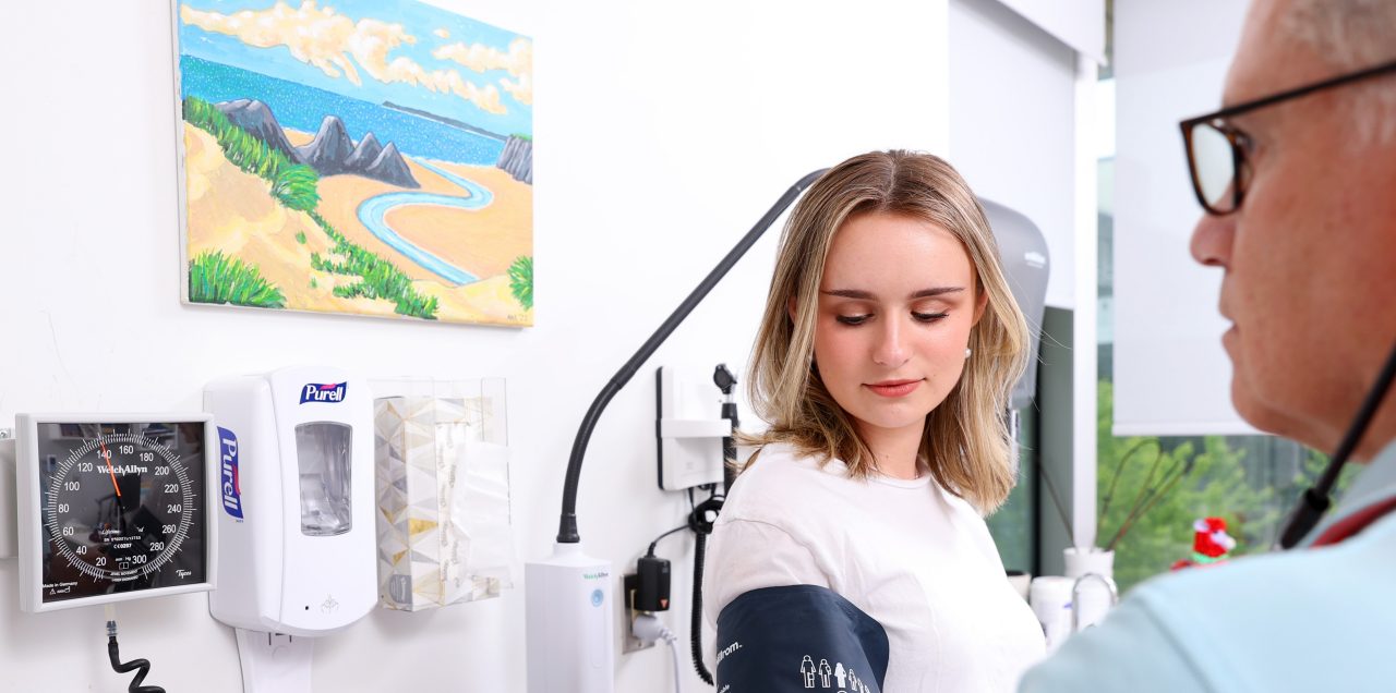 Doctor sitting across from student in a doctor's office.