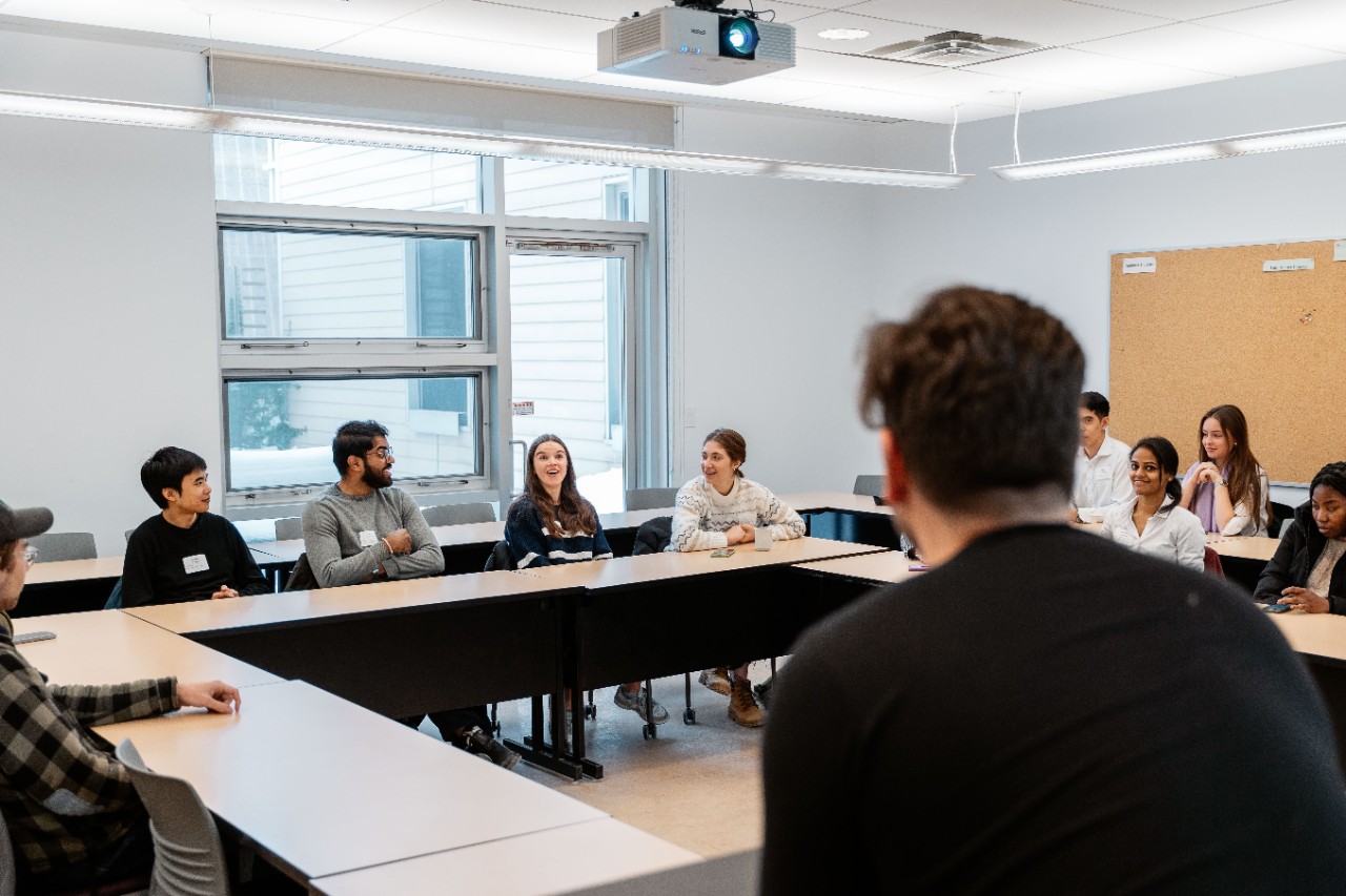 a classroom ffull of students sitting around a big square table