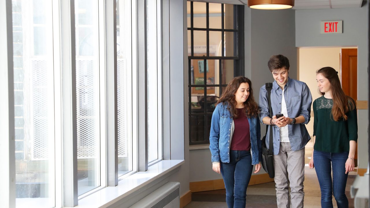 Three residence students walk in a hallway in Howe Hall 